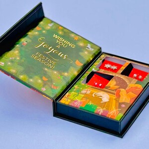 a gift box with a festive design, containing a pair of earrings and a card.
