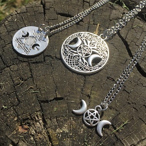 May include: Three silver-toned pendant necklaces with intricate designs. One features a circle with a geometric pattern, another a Celtic knot design with a pentagram and crescent moons, and the third a pentagram between two crescent moons.