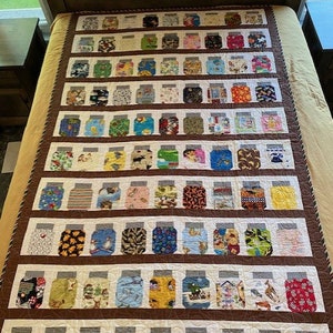 May include: A quilt with a brown background and rows of colourful fabric squares sewn together in the shape of mason jars. The quilt is made up of many different patterns and colours.