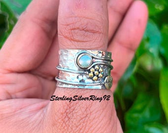 Könnte beinhalten: Ein silberner und goldener Spinnerring mit einem weißen Stein und einem Blattdesign. SterlingSilverRing92.