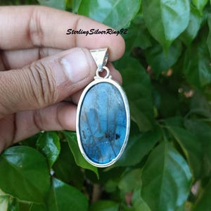 May include: A silver pendant with a blue oval labradorite gemstone. The pendant is on a silver chain.
