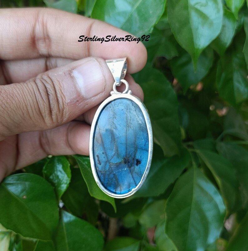 May include: A silver pendant with a blue oval labradorite gemstone. The pendant is on a silver chain.