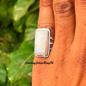 Op de afbeelding: Een rechthoekige sterling zilveren ring met een grote, iriserende, rechthoekige maansteen. De ring heeft een gepolijste zilveren band en een bezel setting. De tekst "Sterling Silver Ring 92" is zichtbaar.