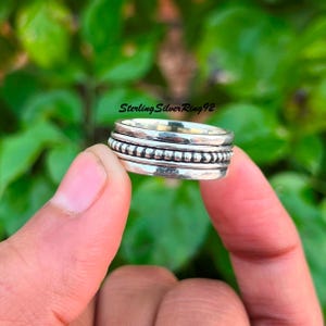 Könnte beinhalten: Ein silberner Drehring mit einem Perlenband. SterlingSilverRing92 ist auf dem Bild gedruckt.