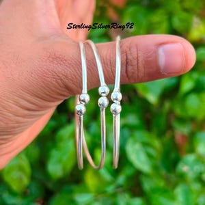Pode incluir: Três pulseiras de prata com três pequenas contas redondas em cada pulseira.