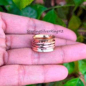 Op de afbeelding: Een draaibare ring gemaakt van meerdere banden van koper en zilver. De ring is gehamerd en heeft een textuur. SterlingSilverRing92 is afgedrukt op de afbeelding.