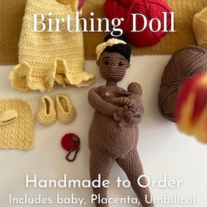 Pode incluir: Boneca de parto de crochê feita à mão com um bebê, placenta e cordão umbilical. A boneca é marrom com uma faixa preta e segura um bebê. Itens de crochê adicionais incluem um vestido, sapatos e um chapéu. O texto diz "Custom Crochet Birthing Doll."