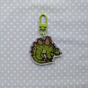 May include: A green and brown cartoon stegosaurus keychain with a lime green metal clasp.