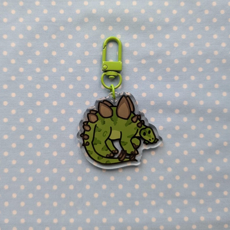 May include: A green and brown cartoon stegosaurus keychain with a lime green metal clasp.