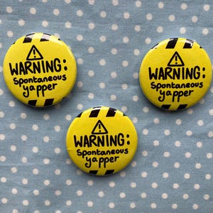 May include: Three yellow and black warning buttons with the text "WARNING: Spontaneous yapper" on each.