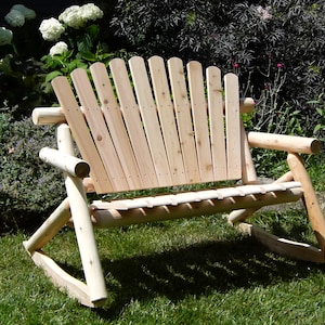 May include: A wooden rocking chair with a slatted back and armrests. The chair is made of natural wood and has a rustic look.