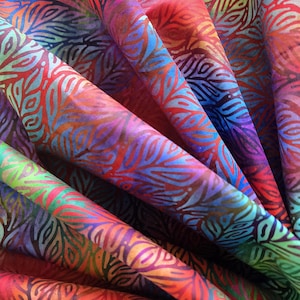 May include: Close-up of a vibrant fabric with a repeating leaf pattern. The fabric features a spectrum of colors, including red, orange, purple, blue, and green. The leaf design is detailed and adds texture to the material.