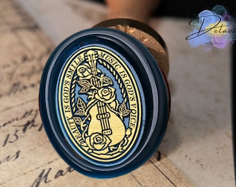May include: A blue wax seal with a gold design of a guitar and roses. The text around the design reads "Beauty is God's Smile Music is God's Voice".