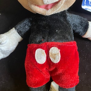 K&ouml;nnte beinhalten: Ein Pl&uuml;sch-Mickey-Mouse-Spielzeug mit schwarz-wei&szlig;em Fell, roten Shorts und gelben Schuhen. Das Spielzeug hat ein wei&szlig;es Etikett mit der Aufschrift "Disney".
