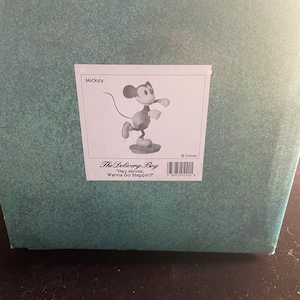 May include: Black and white figurine of Mickey Mouse in a red and yellow outfit, with the text "The Delivery Boy" and "Hey Minnie, Wanna Go Steppin?" on the box.
