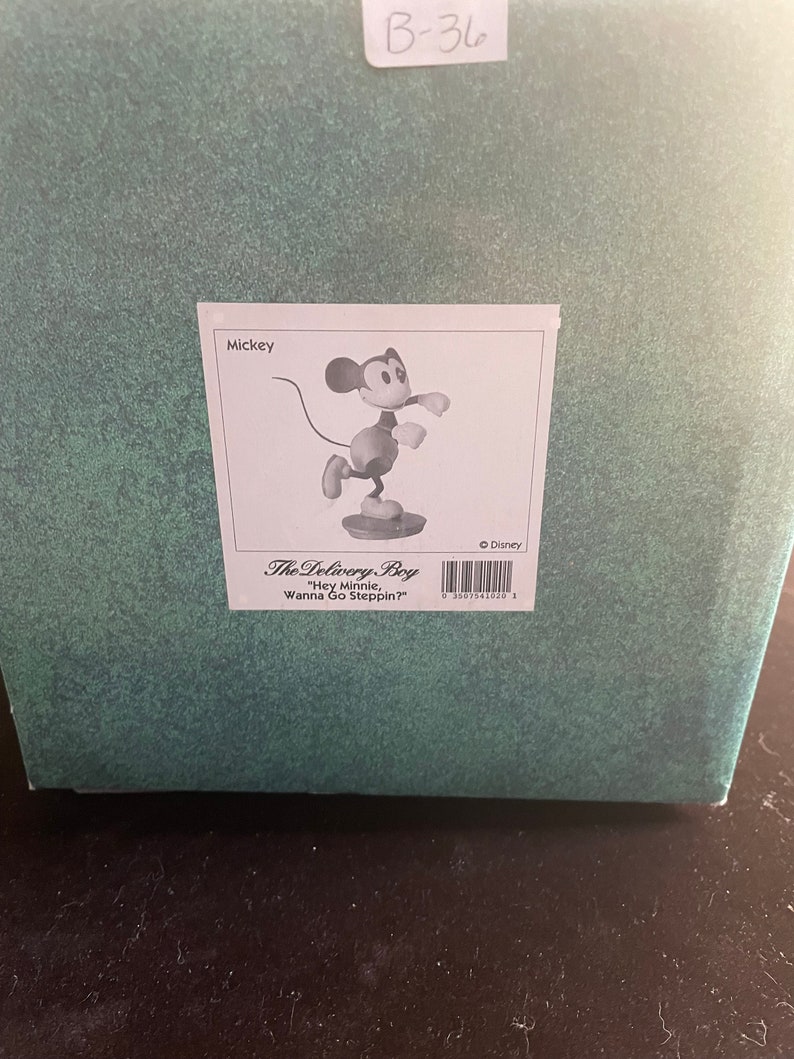 May include: Black and white figurine of Mickey Mouse in a red and yellow outfit, with the text "The Delivery Boy" and "Hey Minnie, Wanna Go Steppin?" on the box.