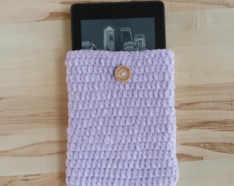 May include: A lavender crocheted e-reader case with a wooden button. The case is made with a soft, fuzzy yarn.