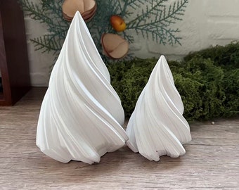 Puede incluir: Dos árboles de Navidad de cerámica blanca con un diseño de espiral. El árbol más grande está a la izquierda y el más pequeño a la derecha.