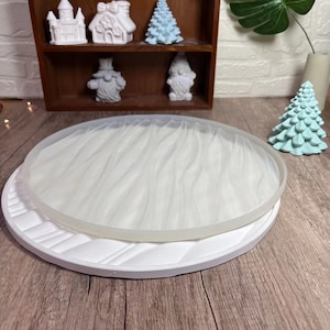 May include: A white round silicone mold with a wood grain texture. The mold is on a white base with a decorative pattern. The mold is used for resin crafts.