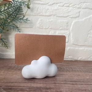 以下が含まれることがあります： 白いセラミック製の雲の形をしたカードホルダーと茶色のカード