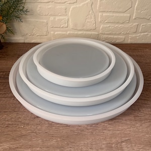 Könnte beinhalten: Satz mit vier runden Silikonformen in Weiß für Kunstharz-Bastelarbeiten. Die Formen sind ineinander verschachtelt, wobei die größte Form unten und die kleinste oben liegt.