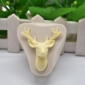 Può includere: Uno stampo in silicone beige a forma di testa di cervo con corna. Lo stampo è progettato per realizzare decorazioni per torte o altri oggetti commestibili.