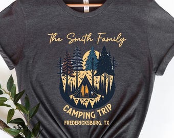 May include: Dark gray t-shirt with a camping-themed graphic. The design features a tent, trees, and a sun, with the text "The Smith Family Camping Trip Fredericksburg, TX" in gold and white.
