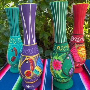 May include: Four hand-painted ceramic vases with colorful designs. The vases are decorated with flowers, birds, and geometric patterns. The vases are all different colors, including green, purple, red, and blue. The vases are all about 10 inches tall. The vases are made in Mexico.