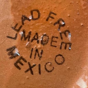 May include: Close-up of a brown ceramic object with the text "Lead Free Made in Mexico" stamped on the bottom.