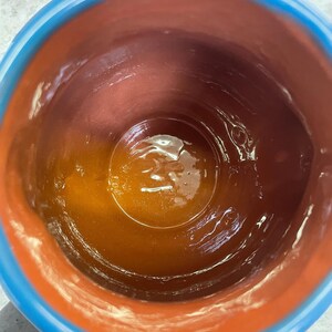 May include: A terracotta pot with a blue rim, the inside is coated with a layer of brown glaze.