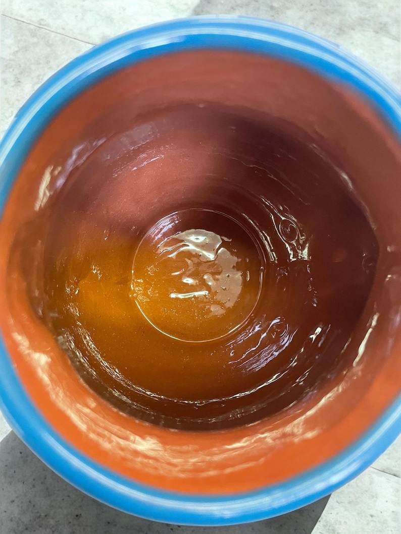 May include: A terracotta pot with a blue rim, the inside is coated with a layer of brown glaze.