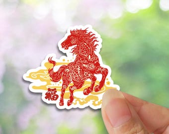 May include: A red sticker featuring a detailed illustration of a horse with intricate patterns. The horse is depicted in a running pose, with the Chinese character for "good fortune" below. The sticker has a white border and a yellow cloud design.