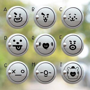 May include: A set of nine circular white buttons, each featuring a distinct black graphic character face. The buttons are labeled A through I in black text. Each button has a small circular protrusion on the left side of the outer rim.