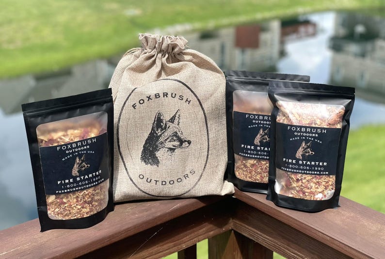 May include: A collection of fire starters from Foxbrush Outdoors. The image shows a burlap sack with a fox logo and three black pouches filled with fire starter material. The pouches have a label with the brand name, fox logo, and the words "Fire Starter".