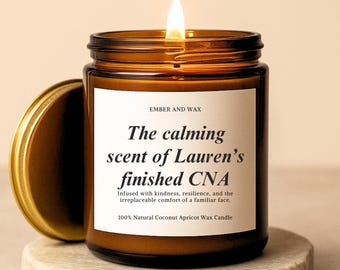 May include: A lit brown glass candle jar with a gold lid, sitting on a stone coaster. The label reads "The calming scent of Lauren's finished CNA." The candle is made of 100% natural coconut apricot wax.
