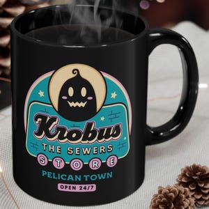 Könnte beinhalten: Schwarze Keramik-Tasse mit dem Text "Krobus The Sewers Store Pelican Town Open 24/7" in einem Retro-Design. Die Tasse hat einen schwarzen Henkel und Dampf, der von oben aufsteigt. Das Design beinhaltet eine Cartoon-Kürbis-Figur.