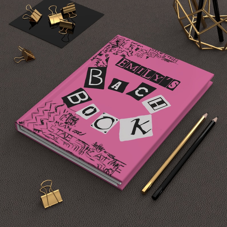 Puede incluir: Cuaderno rosa con el texto "Emily's B.A.C.H. Book" en letras blancas y negras. El cuaderno tiene un borde con un patr&oacute;n blanco y negro.