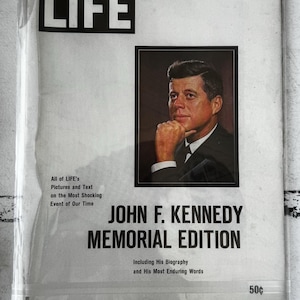 May include: A vintage LIFE magazine John F. Kennedy Memorial Edition with a white cover and a portrait of John F. Kennedy. The text reads LIFE, John F. Kennedy Memorial Edition, All of LIFE's Pictures and Text on the Most Shocking Event of Our Time, Including His Biography and His Most Enduring Words, and 50 cents.