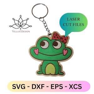 Könnte beinhalten: Ein grüner Frosch-Schlüsselanhänger aus Holz mit roter Schleife und herzförmigen Wangen. Der Frosch hat braune Augen und ist an einem silbernen Schlüsselring befestigt. Der Text "LASER CUT FILES" und "SVG - DXF - EPS - XCS" ist ebenfalls enthalten.