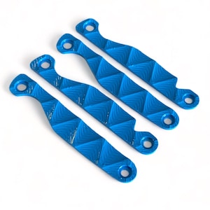 Könnte beinhalten: Vier blaue Metallstücke mit einem Rautenmuster. Jedes Stück hat an jedem Ende ein Loch.