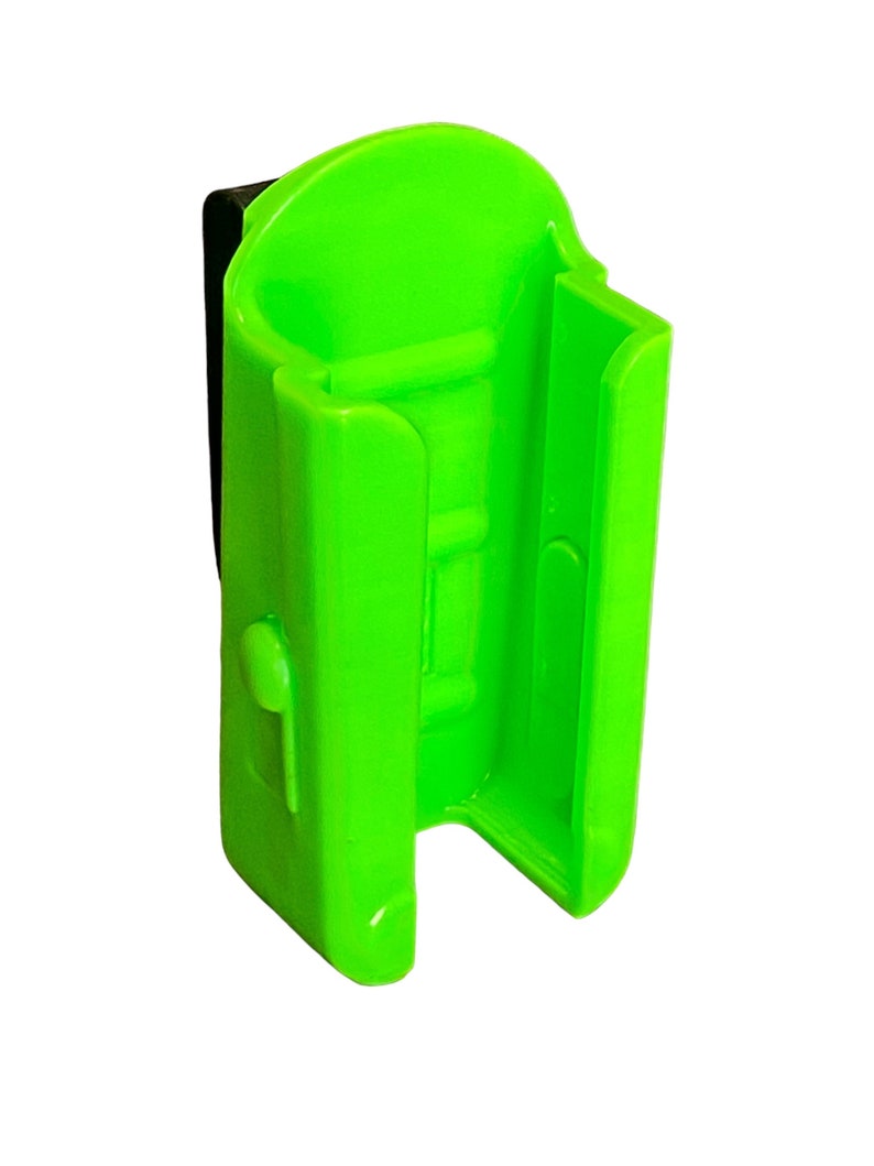 Puede incluir: Un soporte de luz de bicicleta de pl&aacute;stico verde brillante con un clip negro. El soporte tiene una ranura para una luz y un bot&oacute;n de liberaci&oacute;n en el lateral.