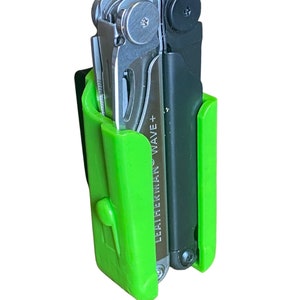 Könnte beinhalten: Ein grünes und schwarzes Multitool-Etui mit einem Leatherman Wave+ Multitool im Inneren. Das Etui hat einen Gürtelclip und einen Knopf an der Seite.