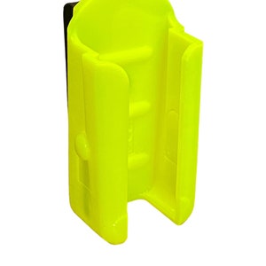 Puede incluir: Un clip de pl&aacute;stico amarillo brillante dise&ntilde;ado para sujetar una linterna u otro objeto peque&ntilde;o. El clip tiene una correa de pl&aacute;stico negro para sujetarlo a un cintur&oacute;n u otra superficie.