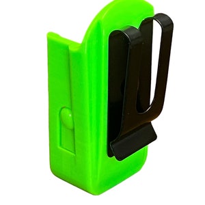 Puede incluir: Un clip de cintur&oacute;n de pl&aacute;stico verde brillante con un clip de metal negro. El clip est&aacute; dise&ntilde;ado para sujetar una linterna u otra herramienta peque&ntilde;a.