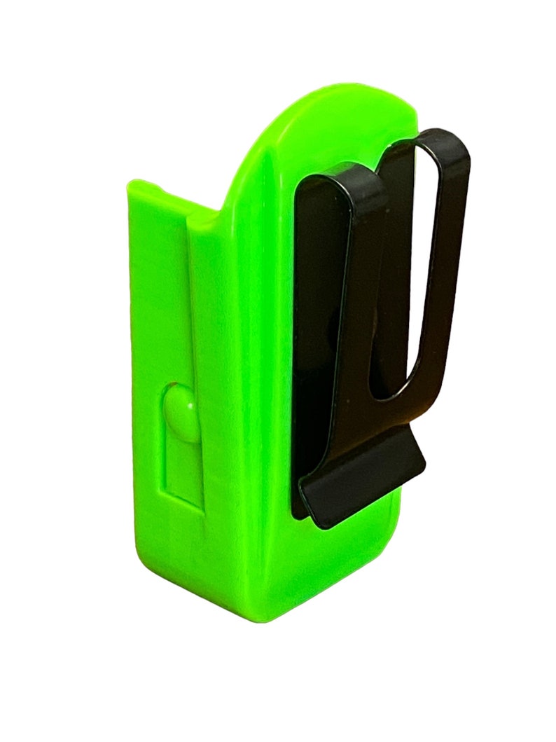 Puede incluir: Un clip de cintur&oacute;n de pl&aacute;stico verde brillante con un clip de metal negro. El clip est&aacute; dise&ntilde;ado para sujetar una linterna u otra herramienta peque&ntilde;a.