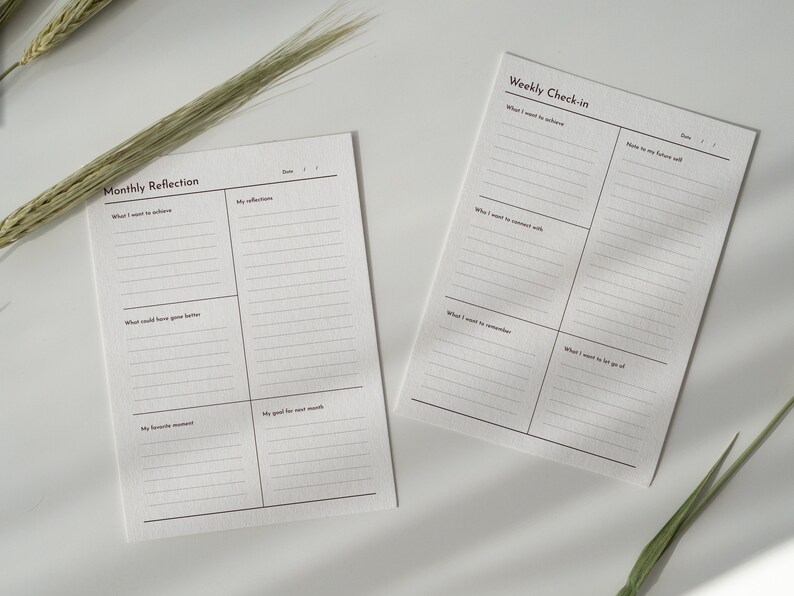 May include: Two printable planner pages with lined sections for weekly and monthly reflection. The pages are titled "Weekly Check-in" and "Monthly Reflection" with sections for "What I want to achieve", "What I want to remember", "My favorite moment", and "My good for next month".