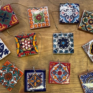 May include: Ten colorful ceramic tile ornaments with intricate patterns in shades of blue, green, red, yellow, and white. Each tile is strung on a gold cord and features a different design.