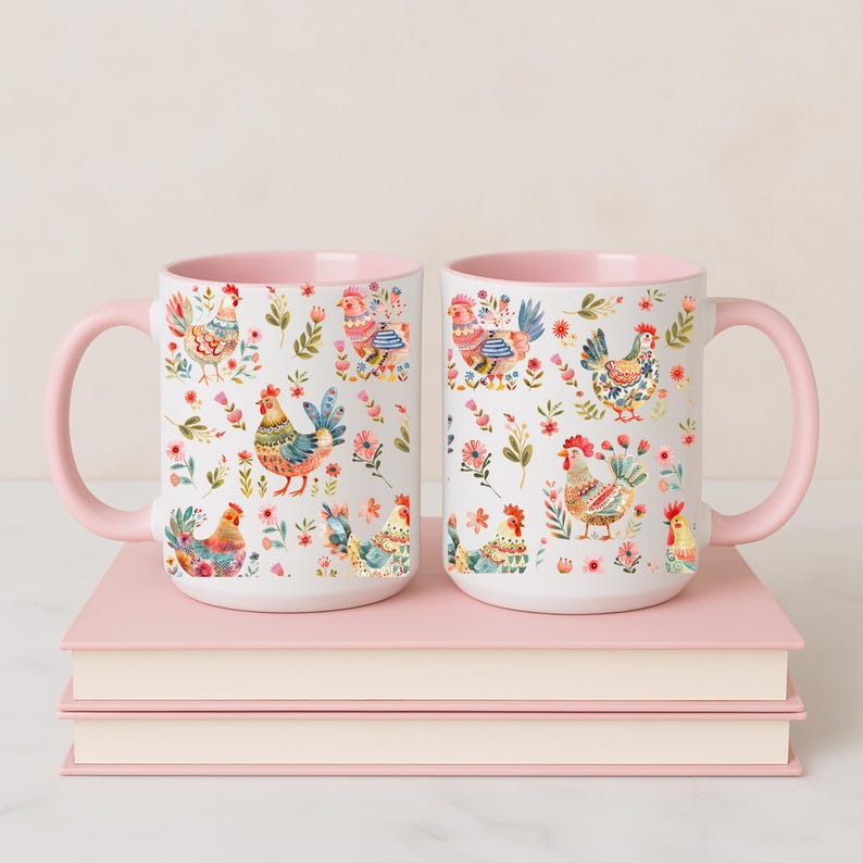 Puede incluir: Dos tazas de cer&aacute;mica blancas con interior y asa rosas. Las tazas presentan un colorido estampado floral y de gallinas. Las tazas est&aacute;n sobre una pila de libros rosas.