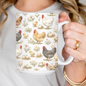 Puede incluir: Taza de cerámica blanca con un patrón repetido de gallinas, pollitos, huevos y elementos florales. Las gallinas están representadas en varios colores, incluyendo marrón, blanco y gris. La taza tiene un asa grande.