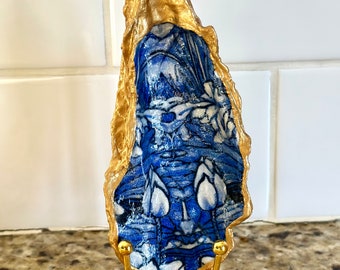 Decoupage abstract blue floral pattern on a hand painted oyster, beach combed on Florida’s Atlantic coast. Gold display stand additional.